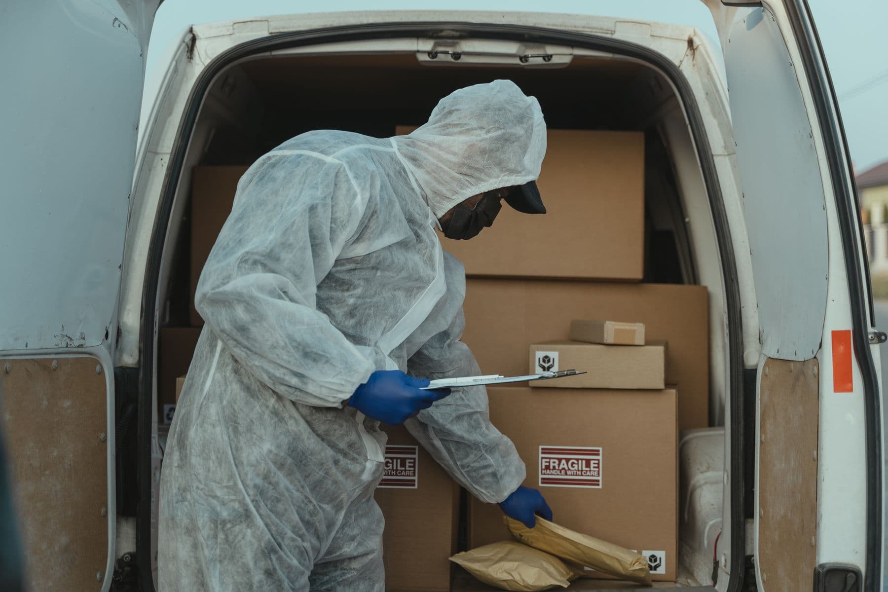 Delivery operative checking multiple parcels inside a loaded van