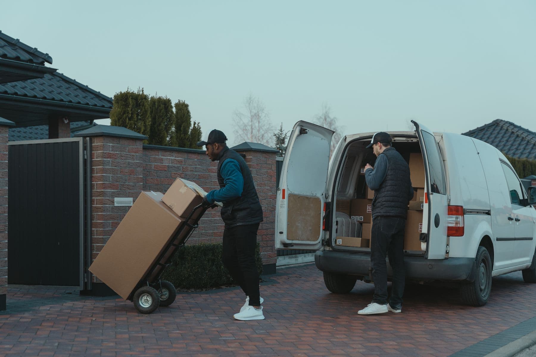 Two delivery operatives moving parcels from the rear of a van