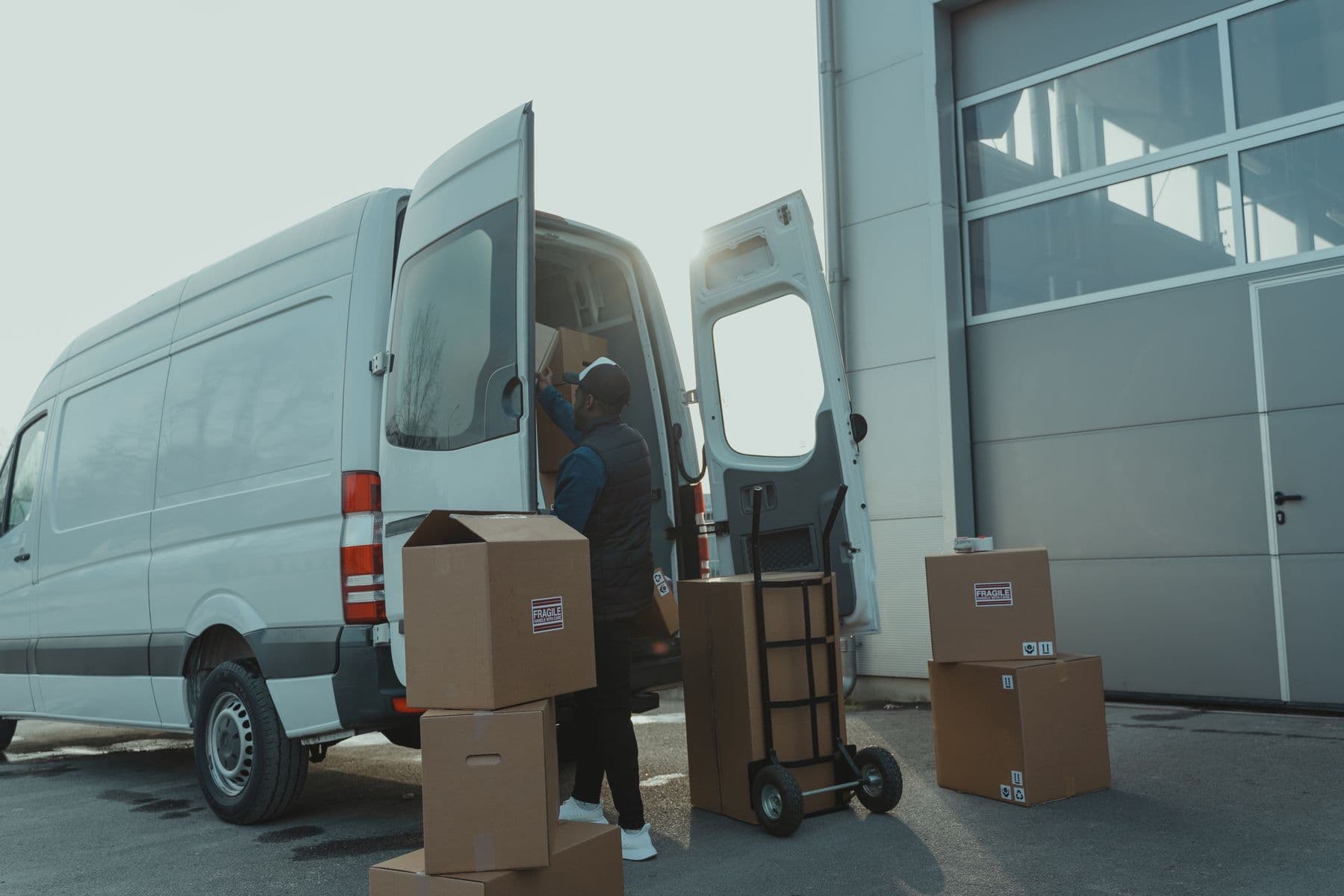 Courier loading prepared cardboard cartons into a delivery van